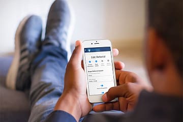 Man sending a referral while relaxing with his feet up